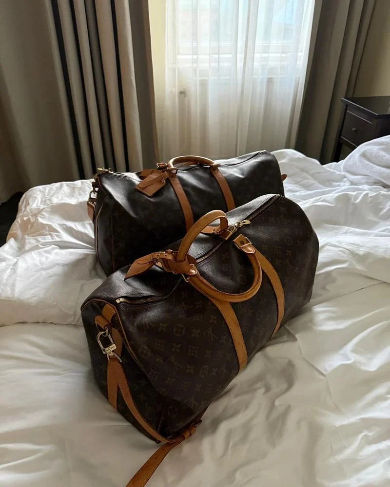 Two vintage monogram designer bags on a bed